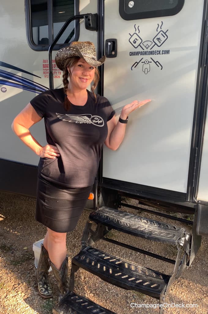 Author of How to Have a Historical & Patriotic Glamping Black Hills Adventure standing in front of her camper wearing a cowboy hat.
